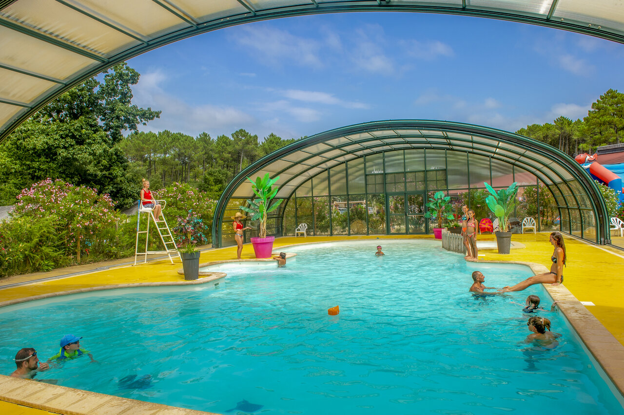 Piscina exterior cubierta con tobog�n y familias en el camping CAPFUN Landisland en Moliets-et-Maa (40).