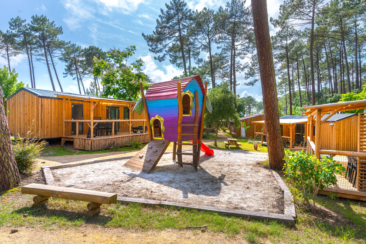 Zona de juegos infantil con caba�a colorida y mobile-homes en el camping CAPFUN Landisland en Moliets-et-Maa (40).