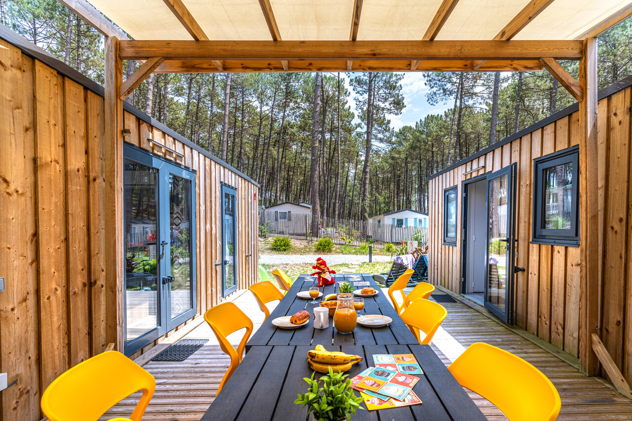 Terraza amueblada con mesa de desayuno frente a mobil-homes en el camping CAPFUN Landisland en Moliets-et-Maa (40).