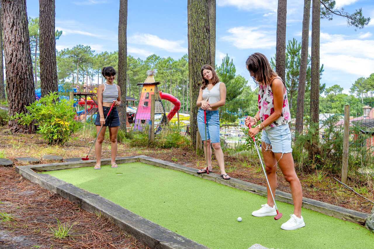 Minigolf con j�venes jugando, rodeado de pinos en el camping CAPFUN Landisland en Moliets-et-Maa.