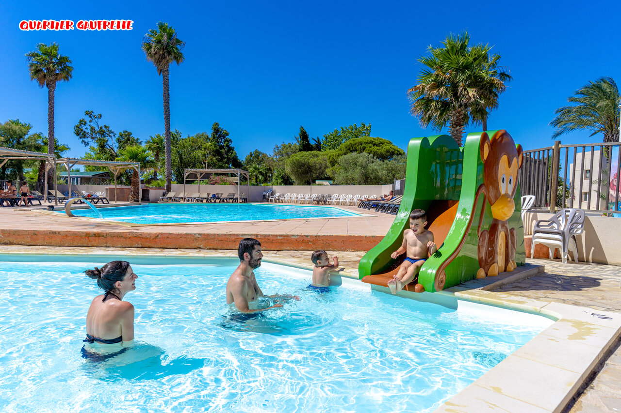 Piscina familiar con tobog�n infantil y palmeras en el camping CAPFUN Las Bousigues en Le Barcar�s (66).