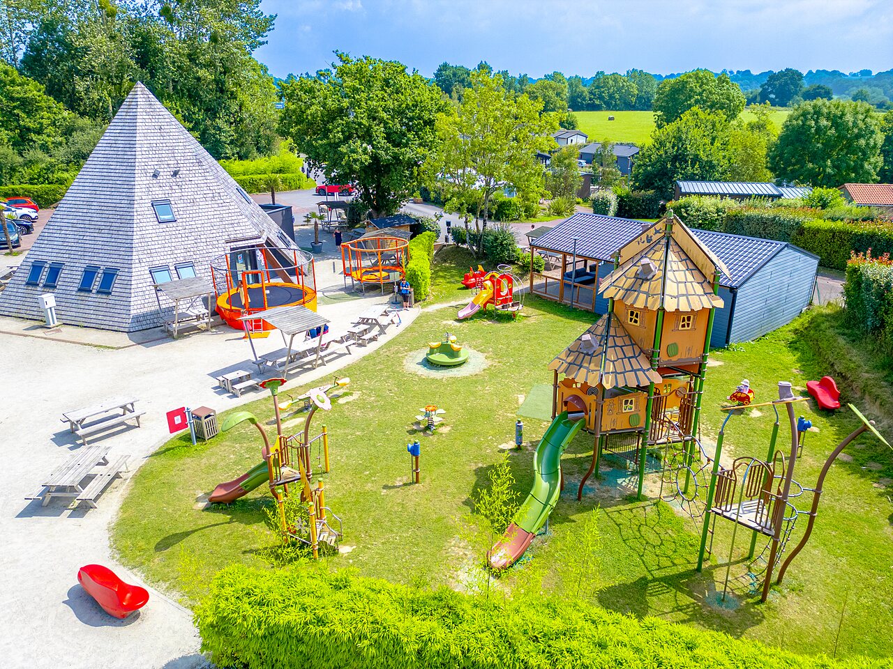 Zona de juegos infantil con toboganes, trampolines en el camping VAGUES OCEANES Les Iles en Hudimesnil (50).