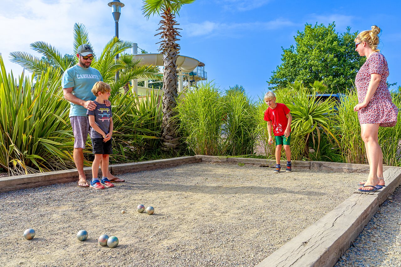 Familia jugando a la petanca en una cancha dedicada en el camping VAGUES OCEANES Les Iles en Hudimesnil (50).