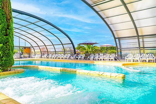 Piscina cubierta y climatizada con sillas en el camping VAGUES OCEANES Les Iles en Hudimesnil (50).