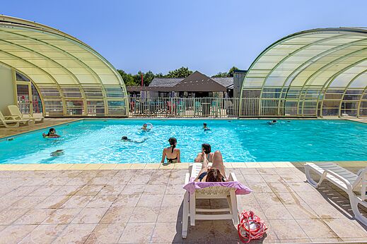 Piscina exterior cubierta con bañistas en el camping CLICOCHIC Bellevue d'Erquy (22).