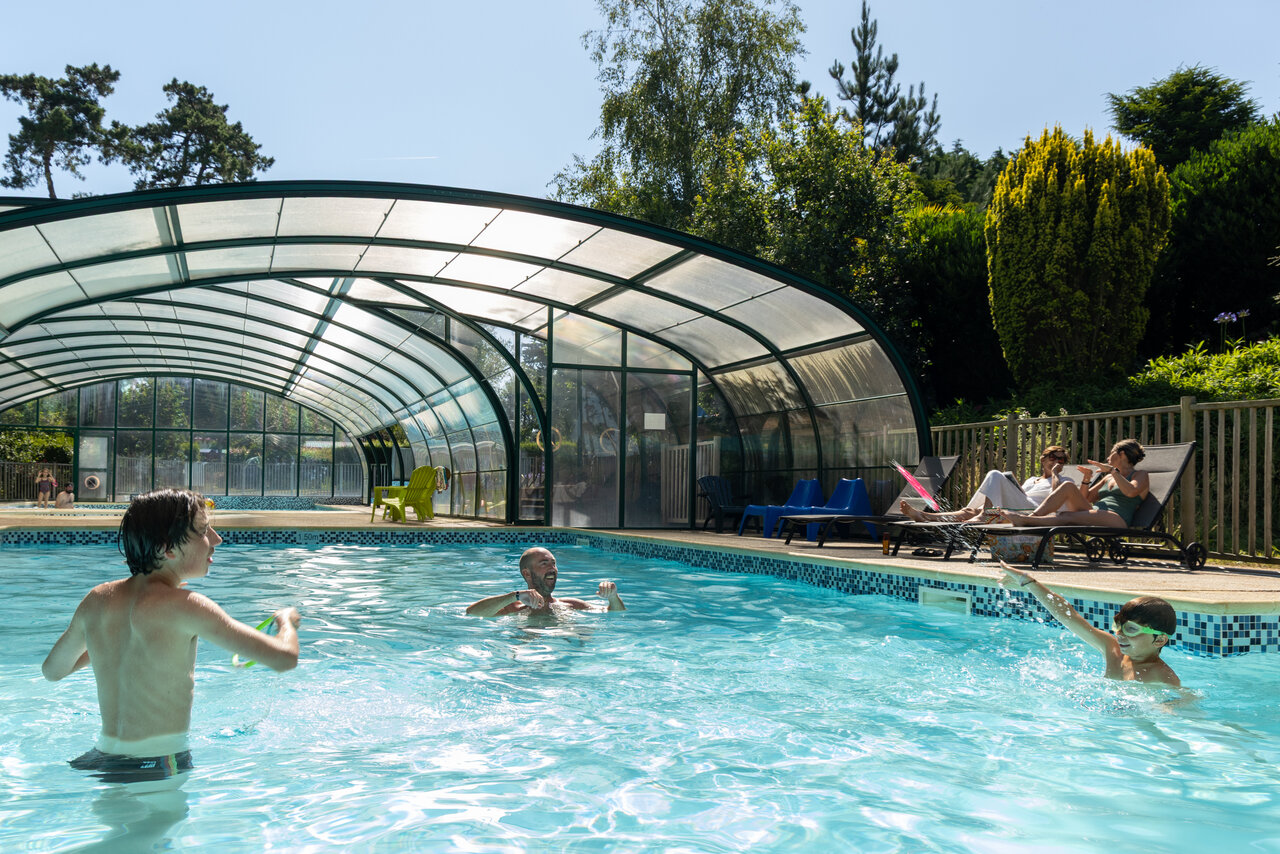 Piscina cubierta y exterior, familia ba��ndose y relaj�ndose en el camping CLICOCHIC Les plages de Beg L�guer en Lannion (22).
