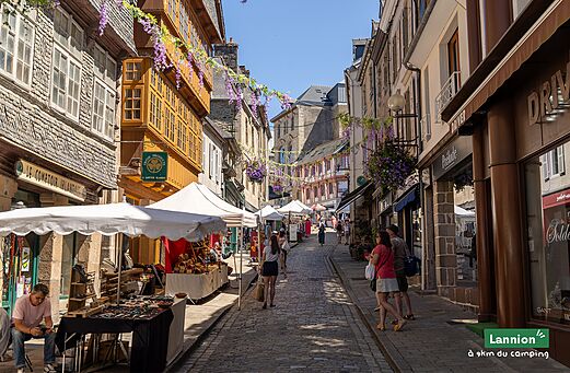Calle comercial animada con mercado artesanal en el casco antiguo de Lannion, Bretaña.
