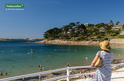 Playa de Trébeurden con bañistas y costa rocosa, un lugar para visitar.