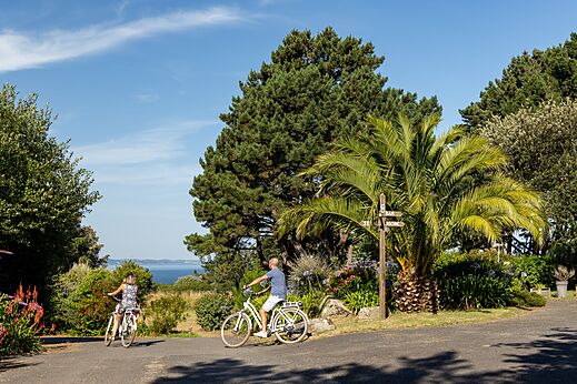 Dos ciclistas en camino arbolado en el camping CLICOCHIC Les plages de Beg Léguer à Lannion (22).