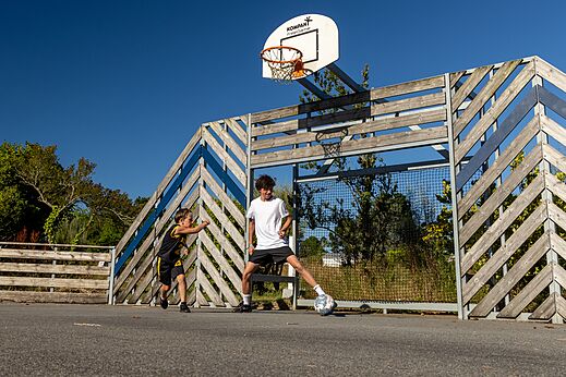 Niños jugando fútbol en cancha multideporte en el camping CLICOCHIC en Lannion.