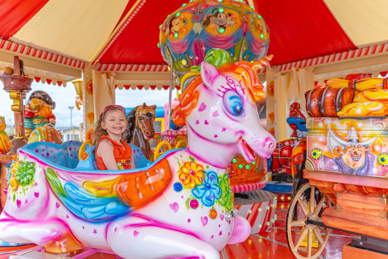 Ni�a sonriente en carrusel de unicornio en el camping VAGUES OCEANES Licorne en Dunkerque (59).