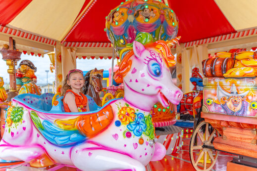Niña sonriente en carrusel de unicornio colorido en camping VAGUES OCEANES Licorne Dunkerque (59).