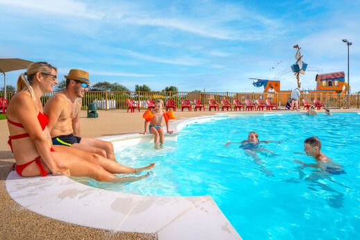 Familia y niños disfrutando de la piscina con juegos acuáticos en el camping VAGUES OCEANES Licorne en Dunkerque (59).