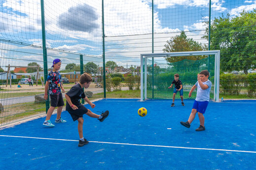 Niños jugando al fútbol en la cancha multideporte del camping VAGUES OCEANES Licorne en Dunkerque (59).