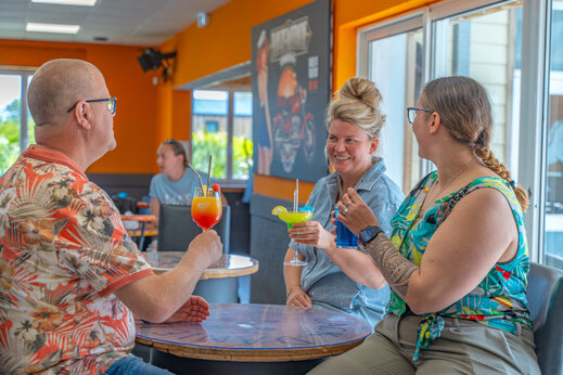 Clientes sonrientes con cócteles en el bar del camping VAGUES OCEANES Licorne en Dunkerque (59).