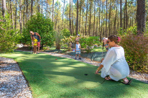 Familia jugando al minigolf en un entorno boscoso en el camping CAPFUN Lila en LINXE (40).