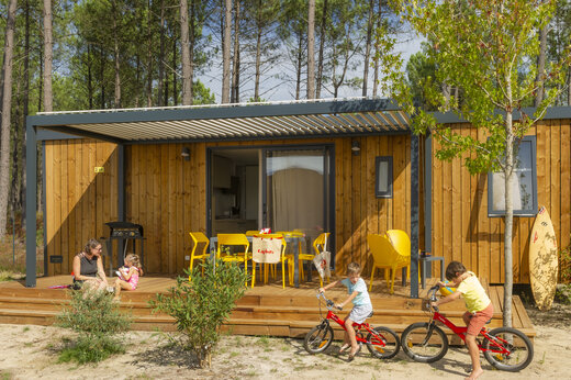 Mobil-home moderno con terraza, familia y niños en bicicleta en el camping CAPFUN Lila en LINXE (40).