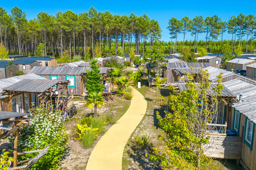 Mobil-homes de madera, camino sinuoso, entorno arbolado en el camping CAPFUN Lila en LINXE (40).