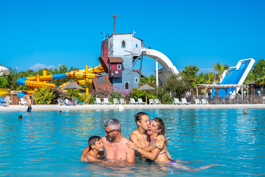 Familia feliz en piscina con toboganes gigantes en camping CAPFUN Lila en LINXE (40).