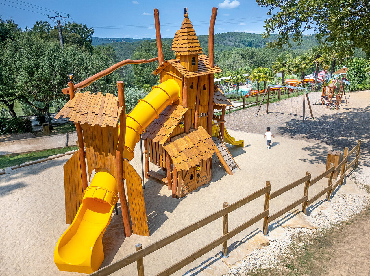 Parque infantil de madera con toboganes amarillos para ni�os en el camping CLICOCHIC Linotte en Le Bugue (24).