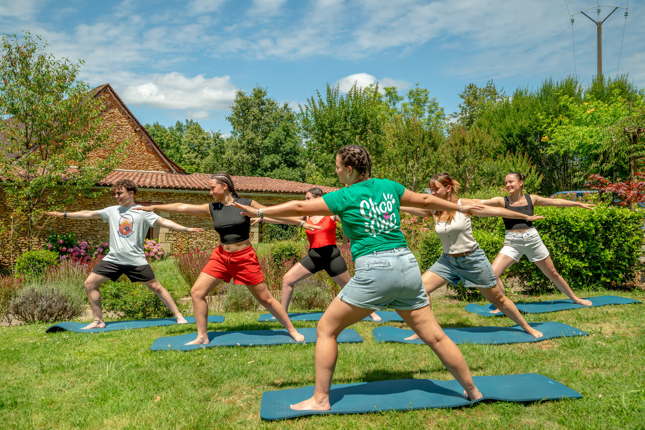 Grupo de personas practicando yoga al aire libre en el camping CLICOCHIC Linotte en Le Bugue (24).