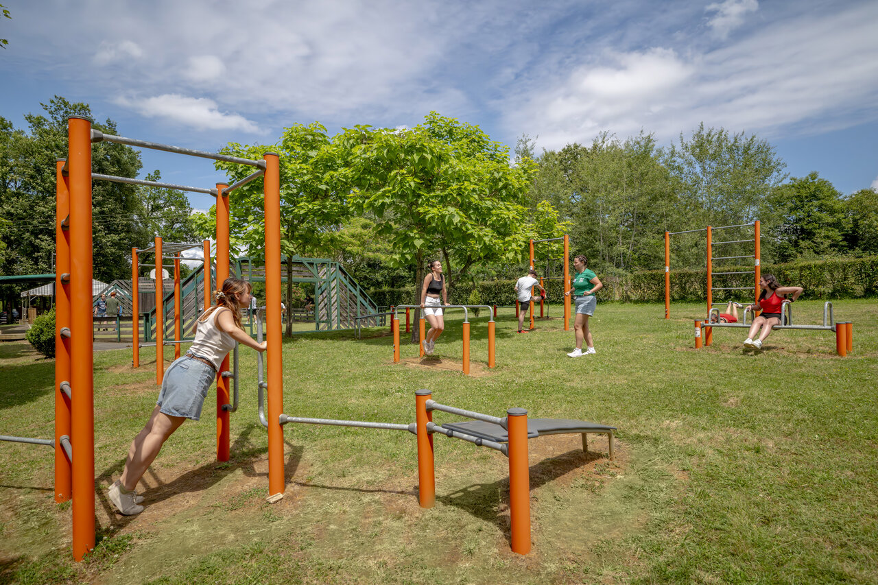 Adultos usando equipos de fitness exterior en el camping CLICOCHIC Linotte en Le Bugue.