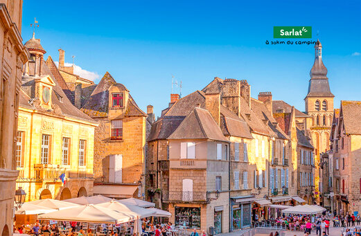 Sarlat, ciudad medieval animada con terrazas de restaurantes en Dordoña.