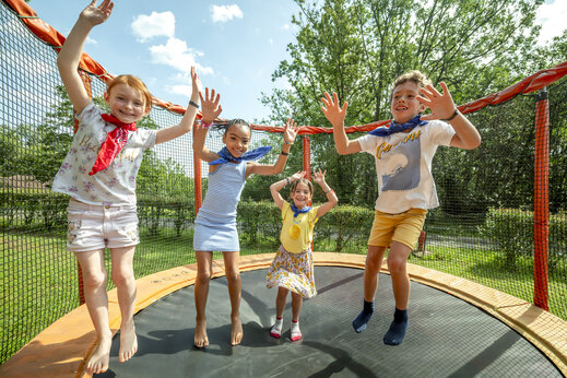 Niños felices saltando en un trampolín seguro en el camping CLICOCHIC Linotte en Le Bugue (24).