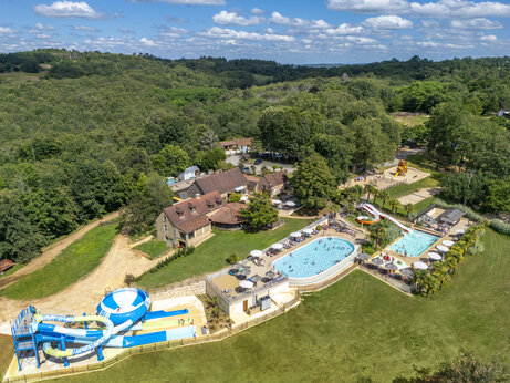 Vista aérea del parque acuático con piscinas, toboganes y juegos en el camping CLICOCHIC Linotte en Le Bugue (24).