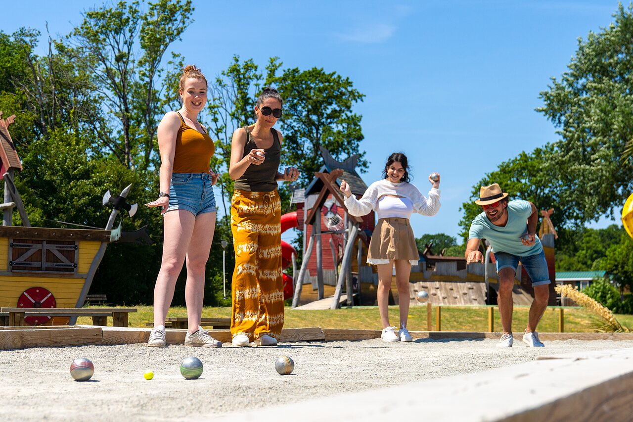 Amigos jugando a la petanca en una cancha soleada en el camping CAPFUN Lodge en SARZEAU (56).
