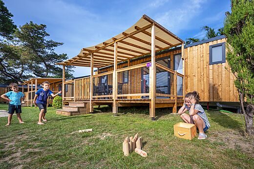 Mobil-homes de madera y niños jugando en el camping CLICOCHIC Longchamp en Saint Lunaire (35).