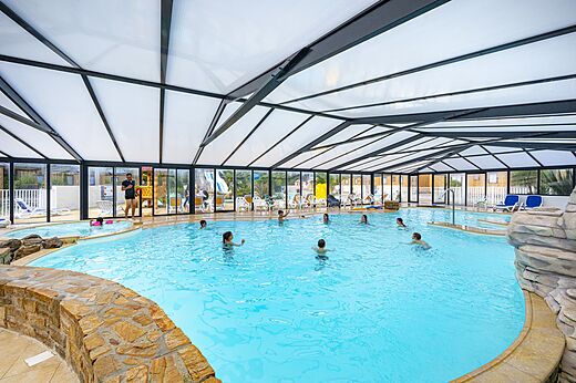 Piscina cubierta con jacuzzi y bañistas en el camping CLICOCHIC Longchamp en Saint Lunaire (35).
