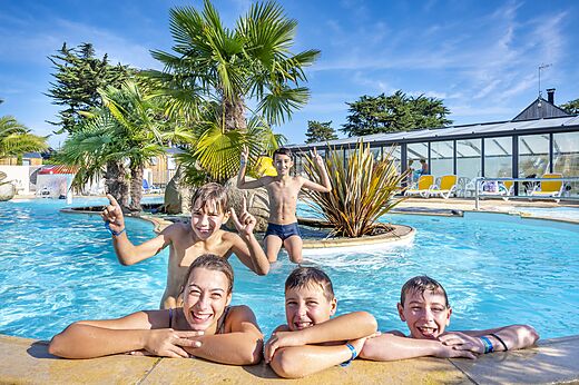 Niños y adolescentes sonriendo disfrutando de la piscina exterior en el camping CLICOCHIC Longchamp en Saint Lunaire (35).