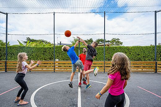 Pista multideporte con niños jugando baloncesto en el camping CLICOCHIC Longchamp en Saint Lunaire (35).