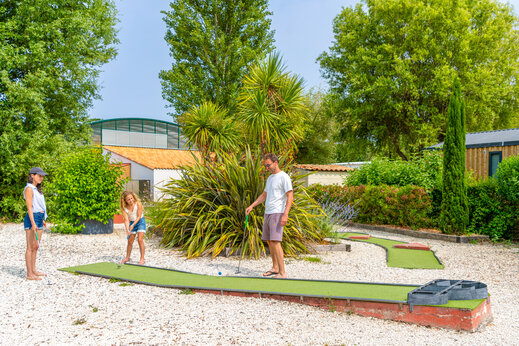 Minigolf con familia jugando en campo verde en el camping CAPFUN Loubine en Les Sables d'Olonne (85).