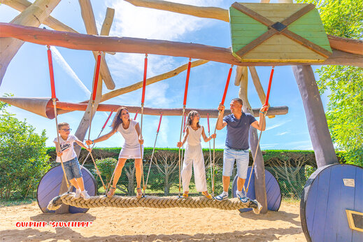 Zona de juegos con puente de cuerda y familia en el camping CAPFUN Loubine Les Sables d'Olonne.
