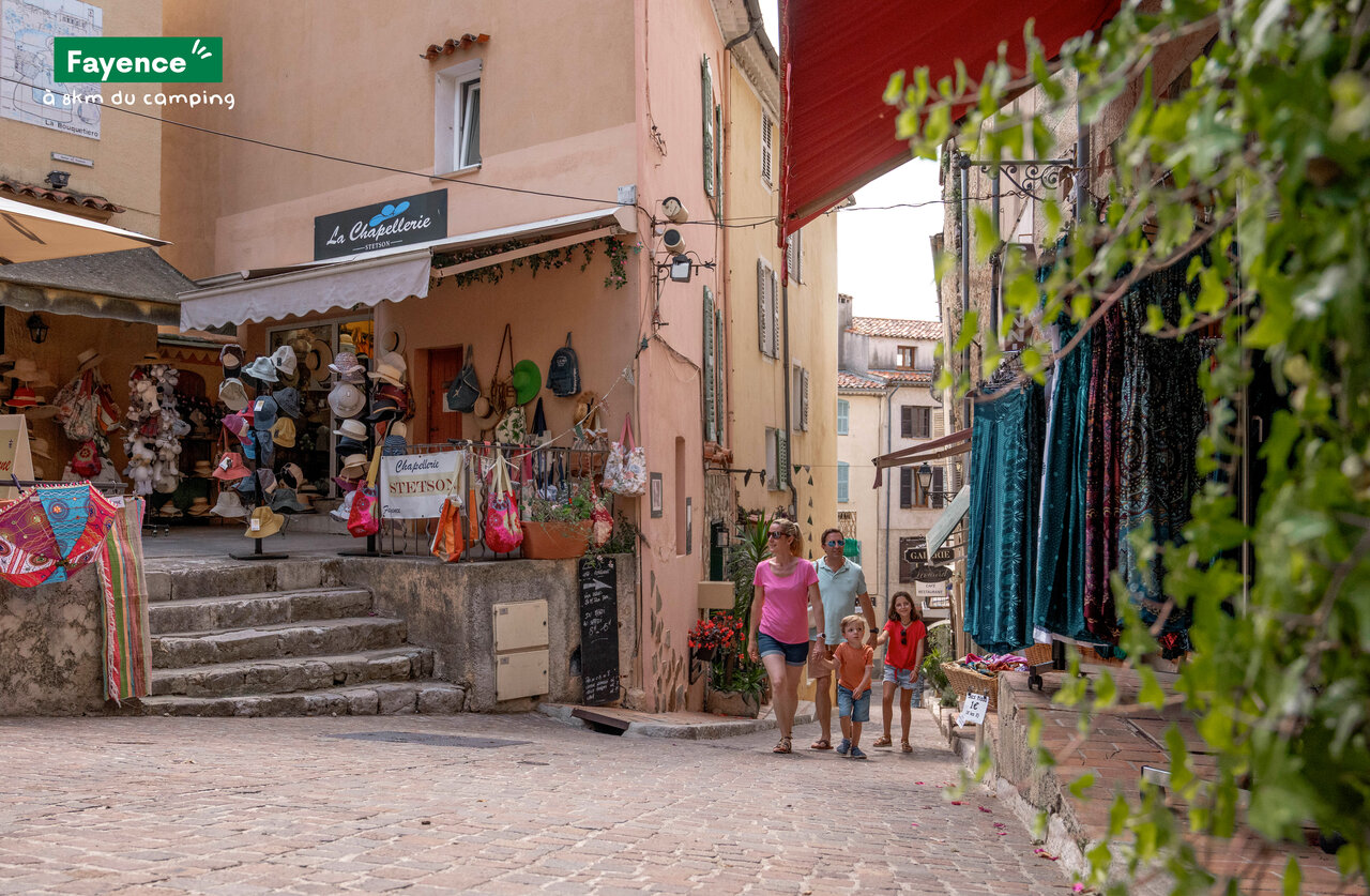 Familia paseando por calle comercial pintoresca de Fayence, Provenza.