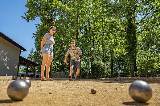 Campo de petanca con jugadores en CLICOCHIC Lou Castel, Castelnaud-la-Chapelle.