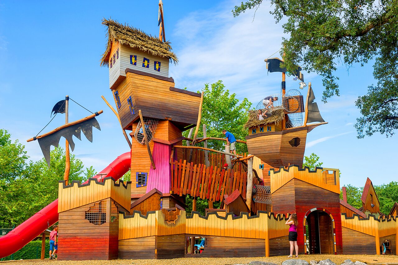 Gran parque infantil de madera tema barco pirata en el camping CAPFUN Lou Puntaou en LEON (40).
