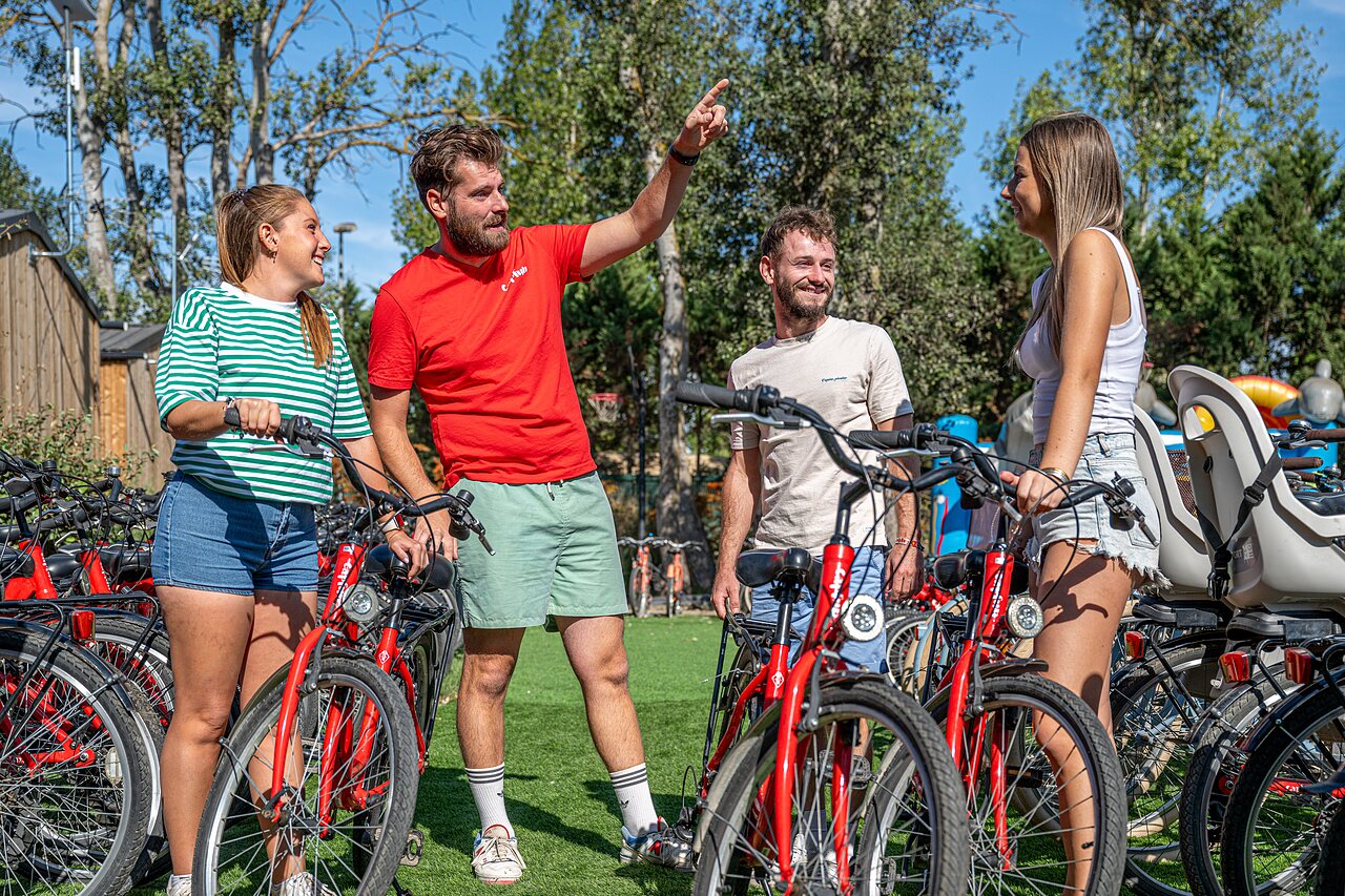 Amigos eligiendo bicicletas rojas en el camping CAPFUN Lou Village en Vendres (34).