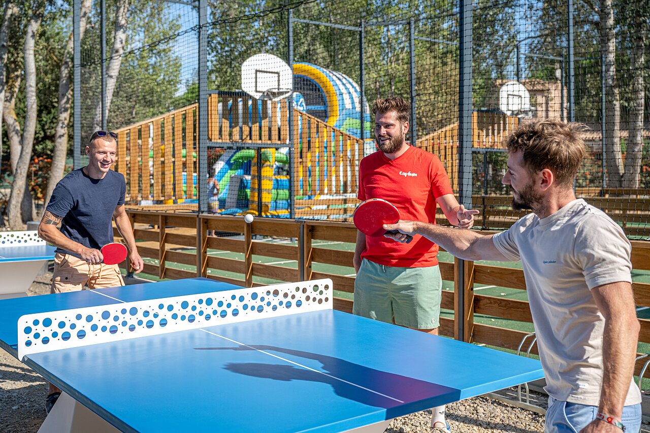 Partido de ping-pong entre amigos, cancha multideporte en el camping CAPFUN Lou Village en Vendres (34).