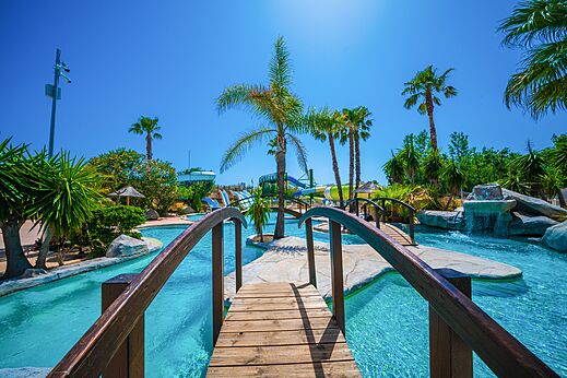 Piscina exterior con toboganes y puentes en el camping CAPFUN Lou Village en Vendres (34).