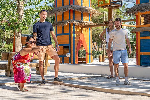 Familia jugando a la petanca en una cancha de juegos en el camping CAPFUN Lou Village en Vendres (34).