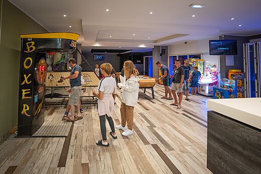 Sala de juegos con máquina de boxeo, futbolín y arcades en camping CAPFUN Lou Village en Vendres (34).