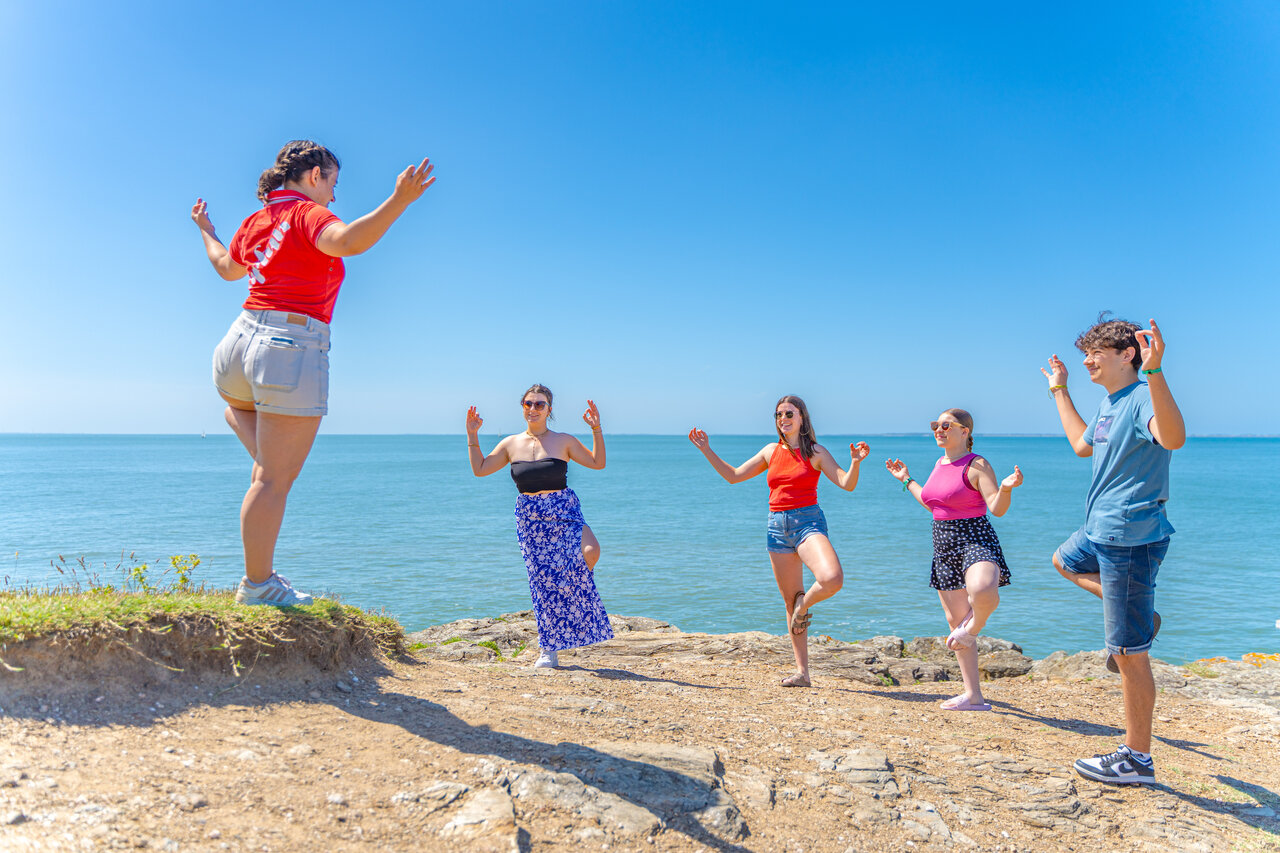 Grupo de amigos practicando yoga frente al mar en camping CAPFUN Madrague en PORNIC (44).