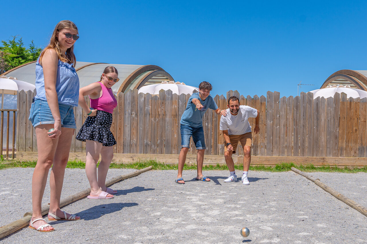 Familia jugando a la petanca en una cancha soleada en el camping CAPFUN Madrague en PORNIC (44).