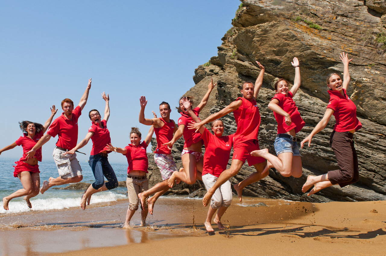 Animadores sonrientes saltando en la playa, camping CAPFUN Madrague PORNIC (44).