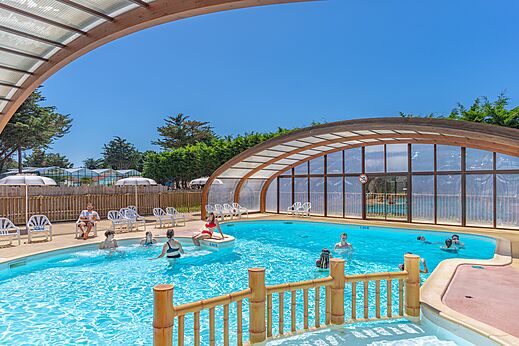 Piscina exterior y cubierta con bañistas en el camping CAPFUN Madrague en PORNIC (44).