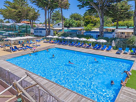 Piscina exterior, bañistas, sillas y sombrillas en el camping CAPFUN Madrague en PORNIC (44).
