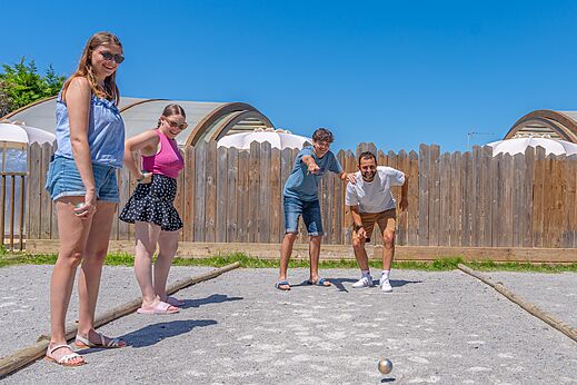 Familia jugando a la petanca en cancha soleada en el camping CAPFUN Madrague en PORNIC (44).